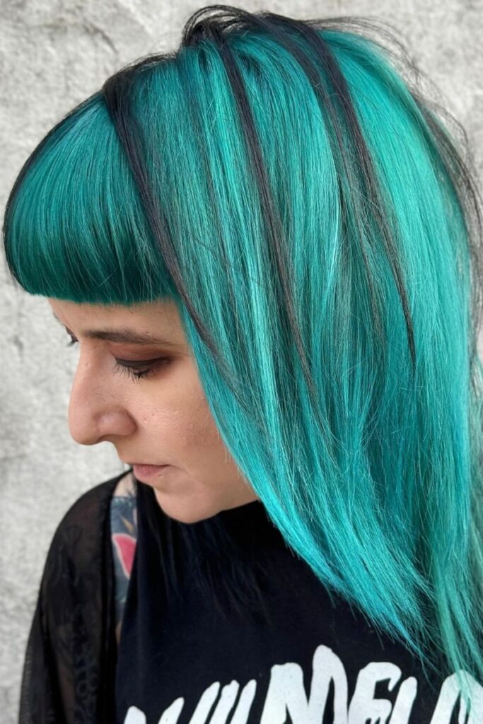 Turquoise blunt bob with black streaks and straight bangs