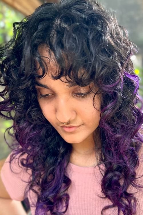 Curly wolf cut with bangs purple highlights