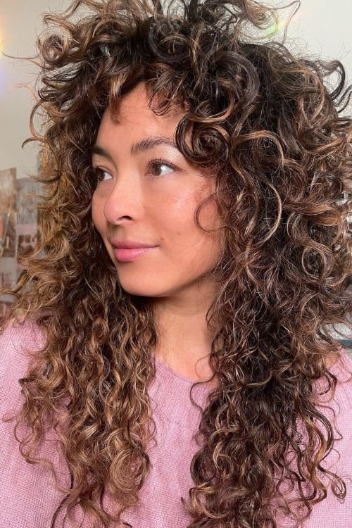 Curly wolf cut with layered curls tousled bangs and voluminous shape