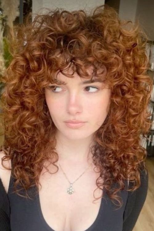 Curly wolf cut with voluminous layers and curly fringe